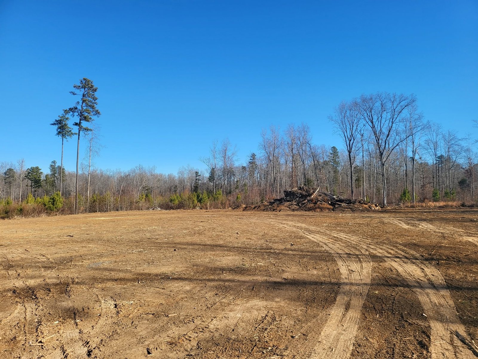 Large cleared and graded building site surrounded by woods